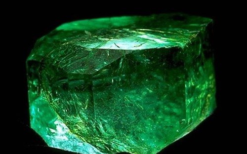 Large green emerald crystal on black