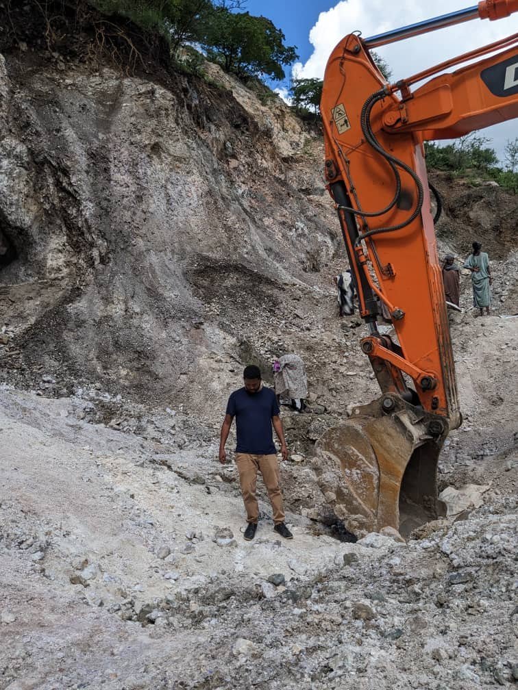 Team member at the mine face beside an excavator